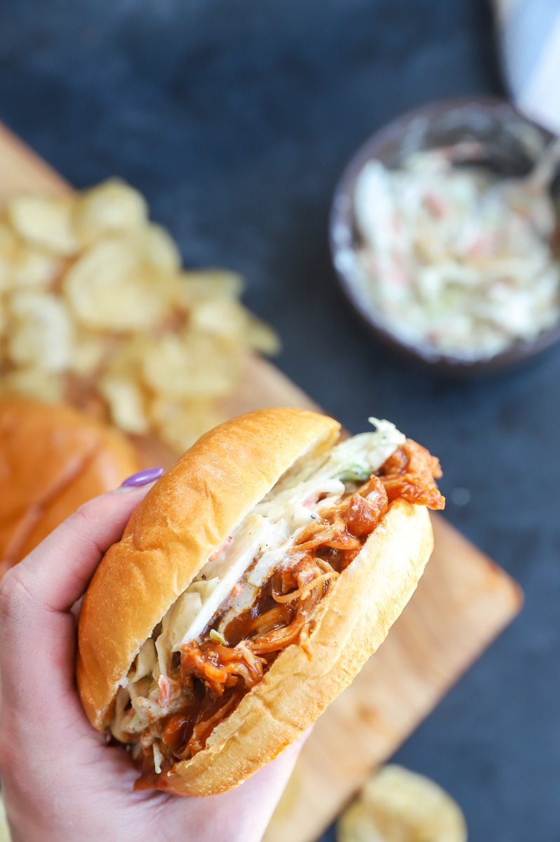 Hand holding a chicken sandwich with coleslaw