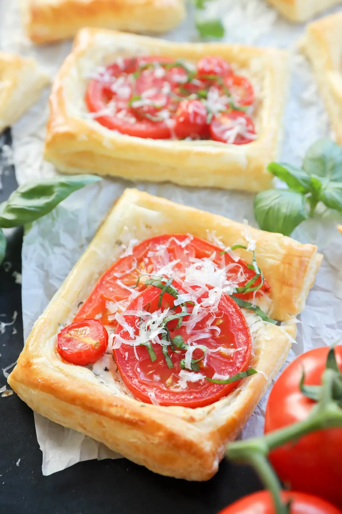 Tomato puff pastry tarts image with herbs on parchment paper image