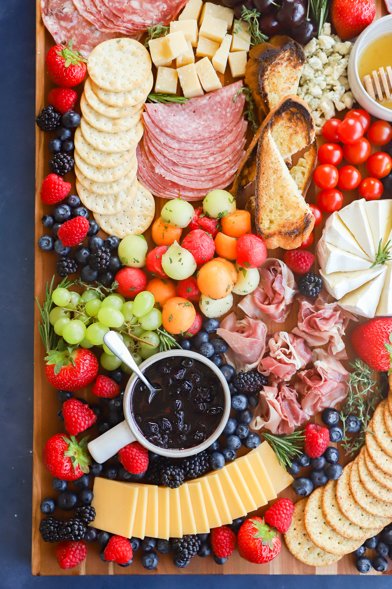 Overhead image of platter of cheeses meats and fruits for summer