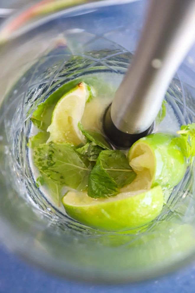 Muddling mint lime and simple syrup in a mixing glass picture