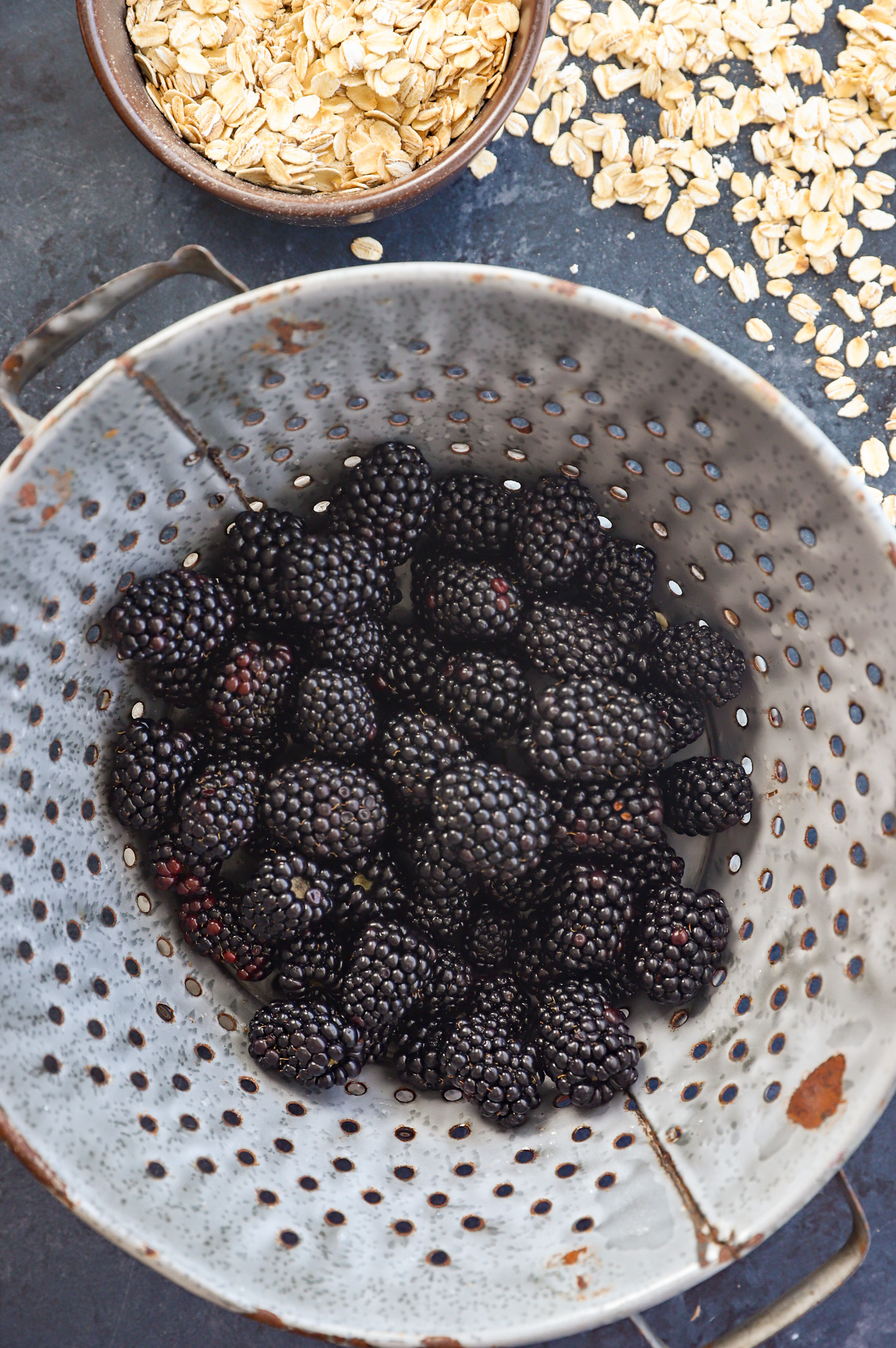 freshly washed blackberries in a colander with oats on the side
