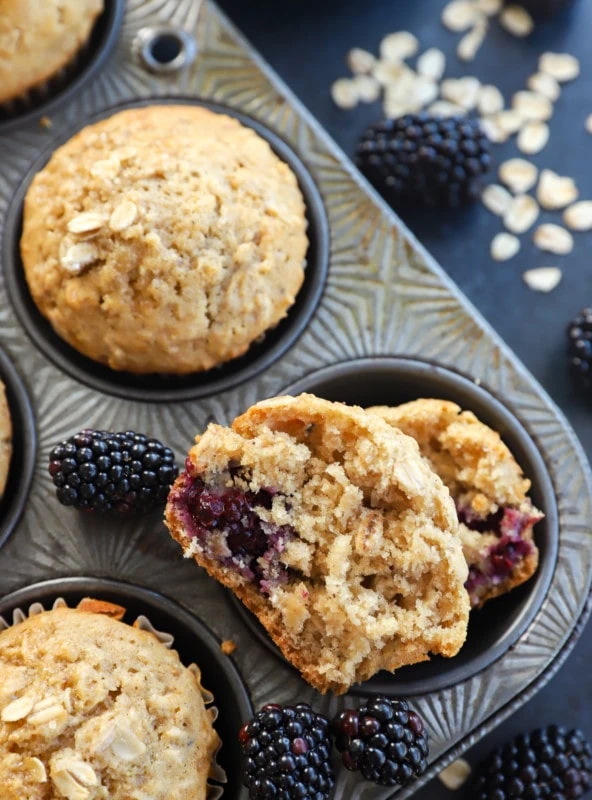 half of a muffin in a muffin tin with fresh berries and oats