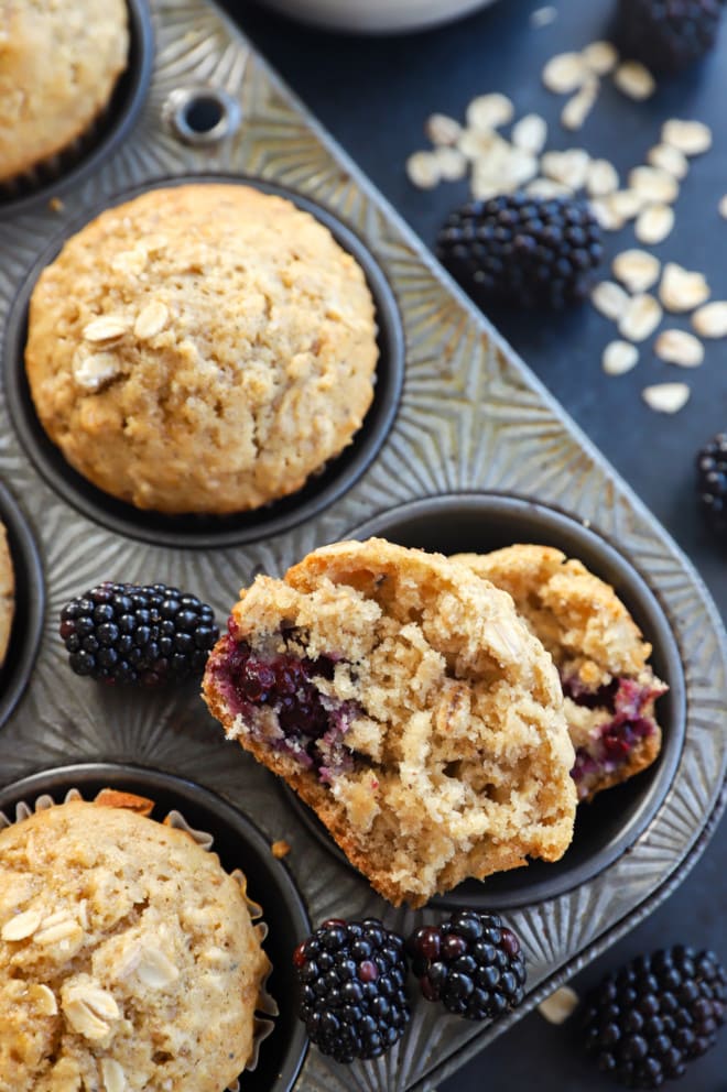 half of a muffin in a muffin tin with fresh berries and oats