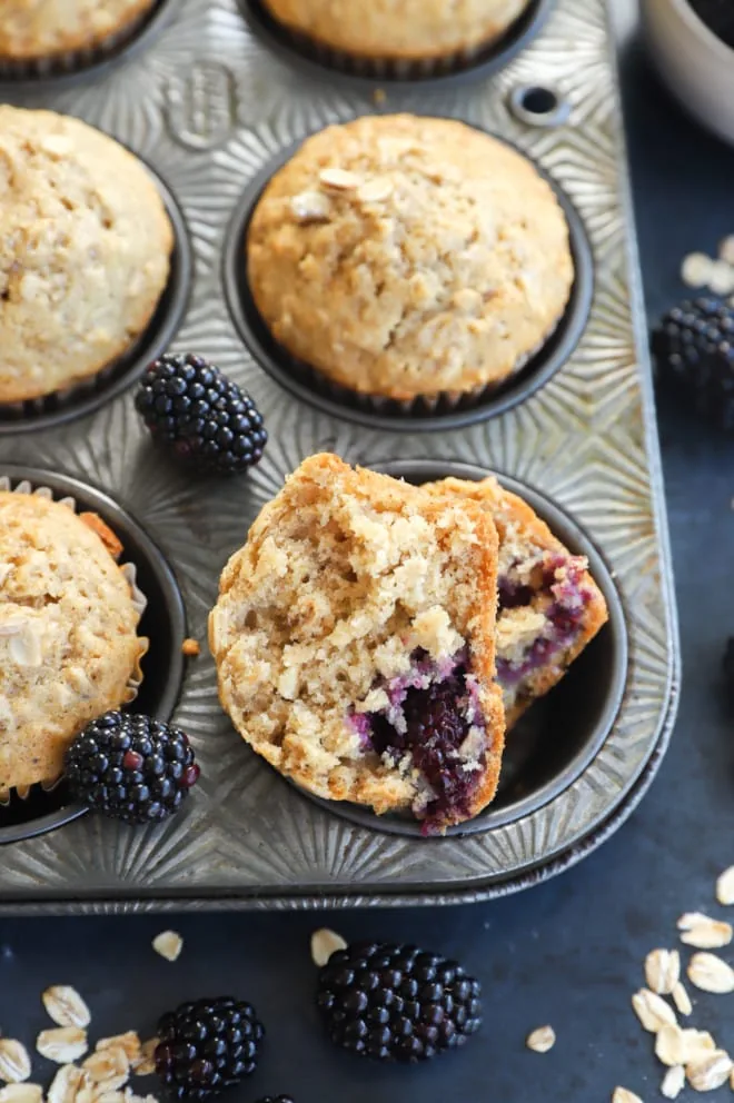 Half of a muffin with whole muffins in a muffin tin