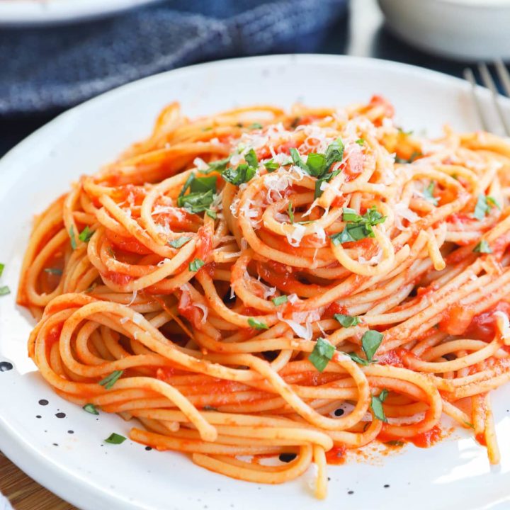 Pasta napolitana on a plate with fresh basil and parmesan