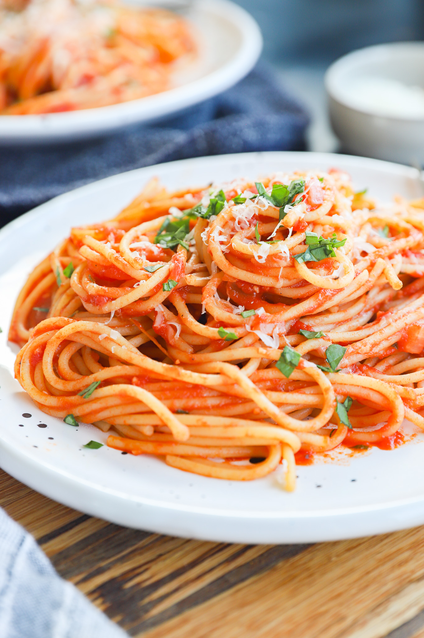 Plate of pasta napolitana topped with fresh basil and cheese