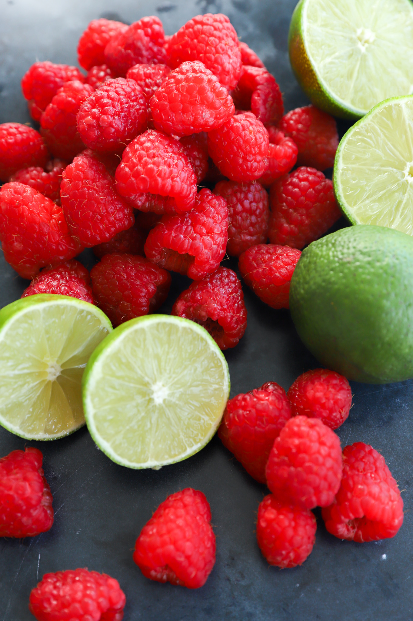 A pile of fresh raspberries and limes ingredients for raspberry daiquiri