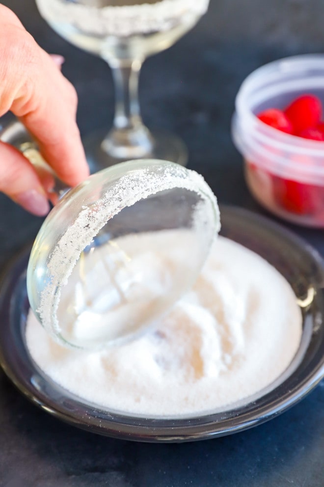 Rolling a cocktail glass in sugar for a sugar rim