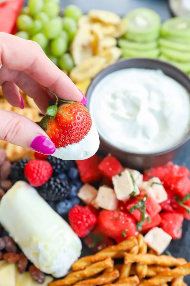 Dipping a strawberry in whipped cream with hand holding the strawberry picture