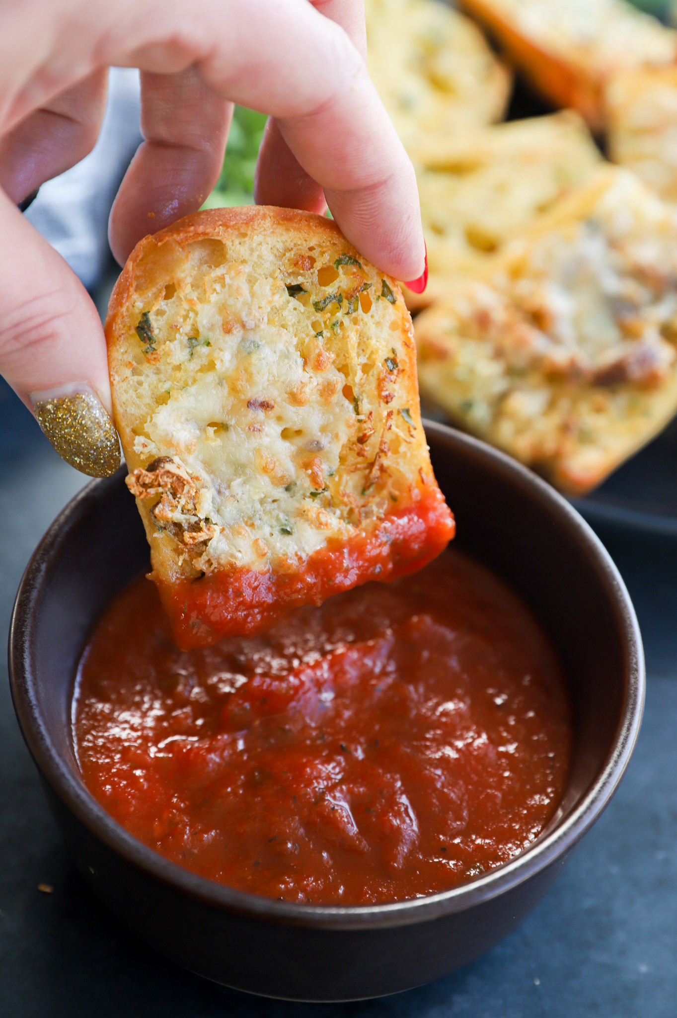 Dipping a piece of air fryer roasted garlic bread