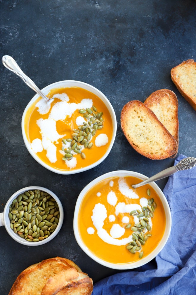 Image of bowls of fall dinner with seeds and cream on top