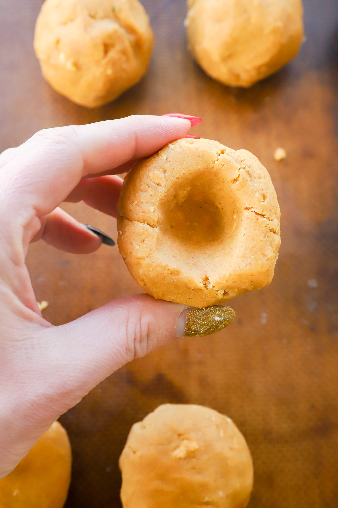 showing how to make an indent in a ball of cookie dough