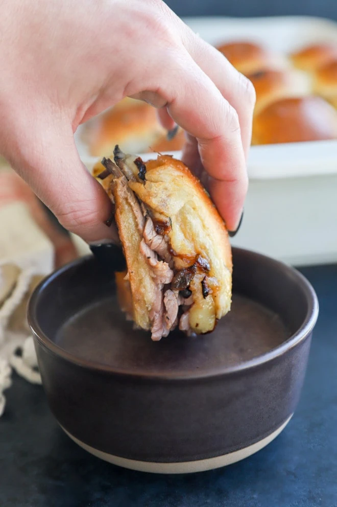 dipping a small sandwich in au jus