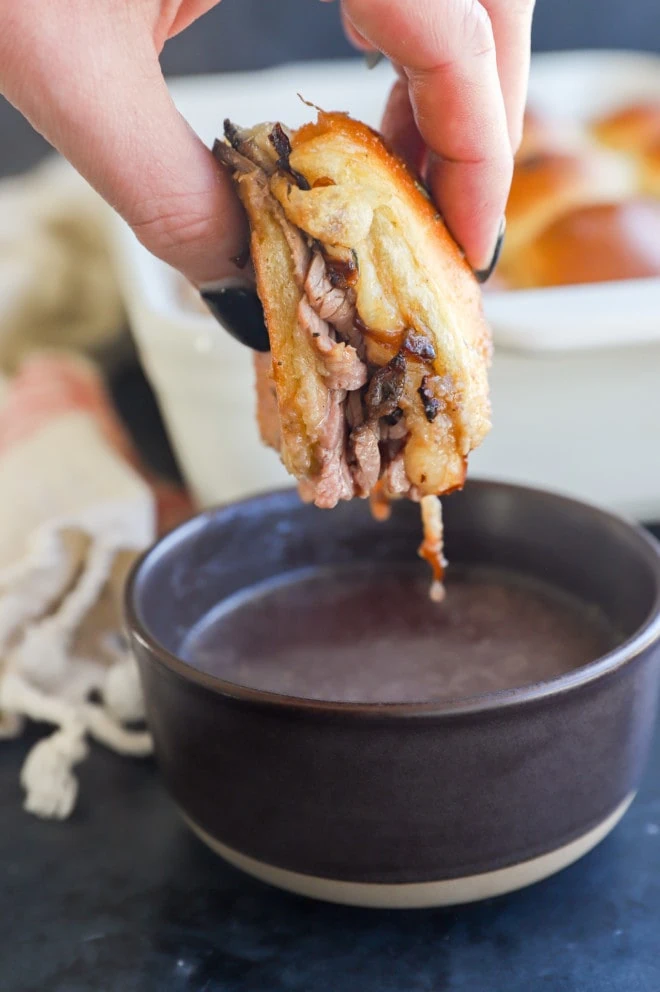 Dipping a roast beef slider into a bowl of beef sauce