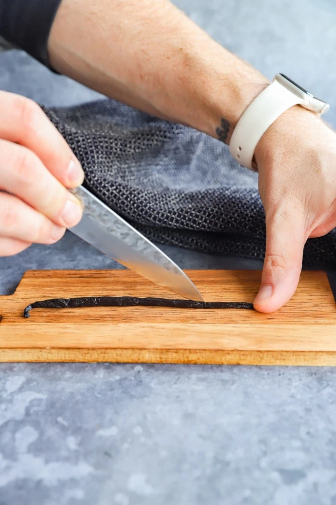 slicing a vanilla bean open on a cutting board