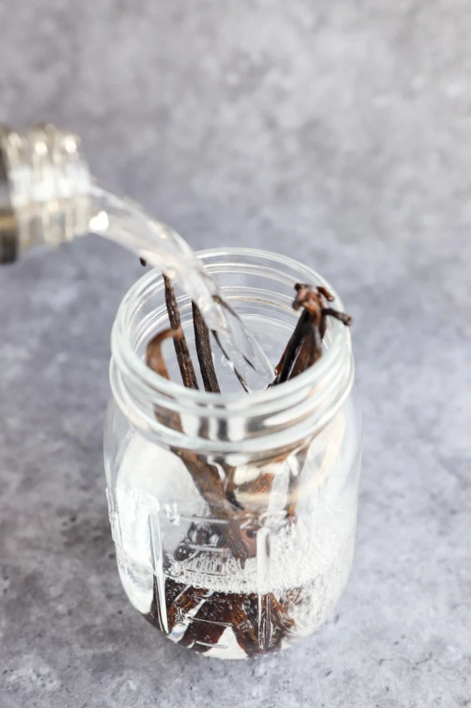 pouring vodka into a jar with beans