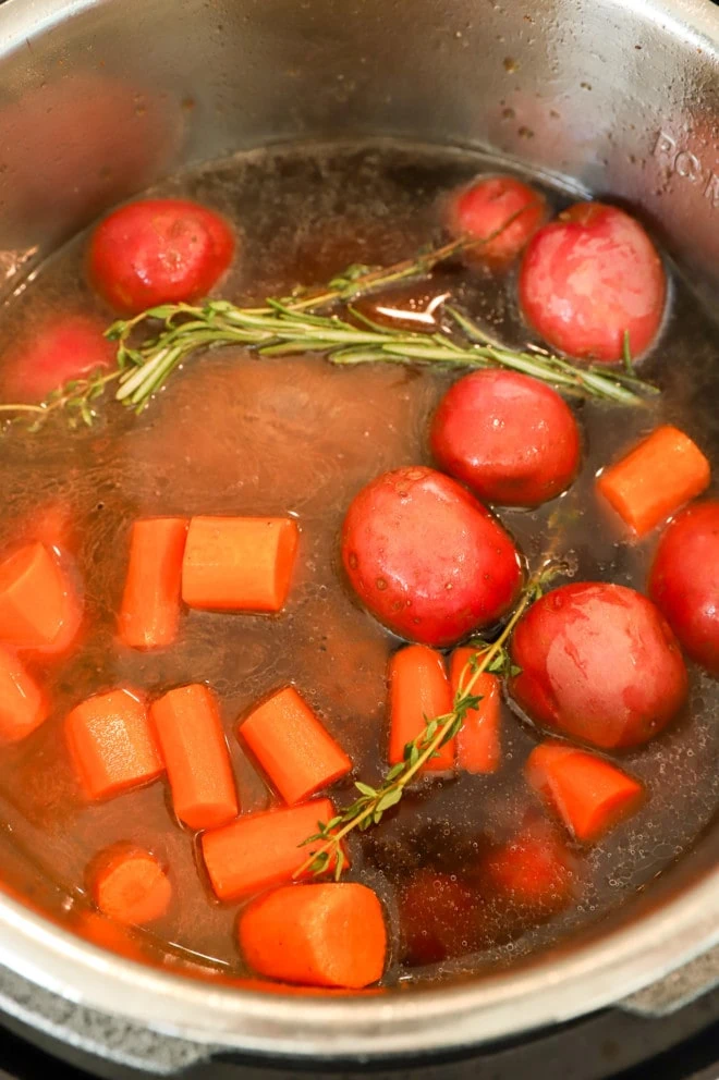 potatoes and carrots on top of seared chuck roast in electric pressure cooker