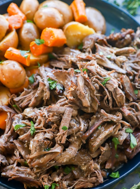 Instant pot roast beef on a plate with vegetables and gravy