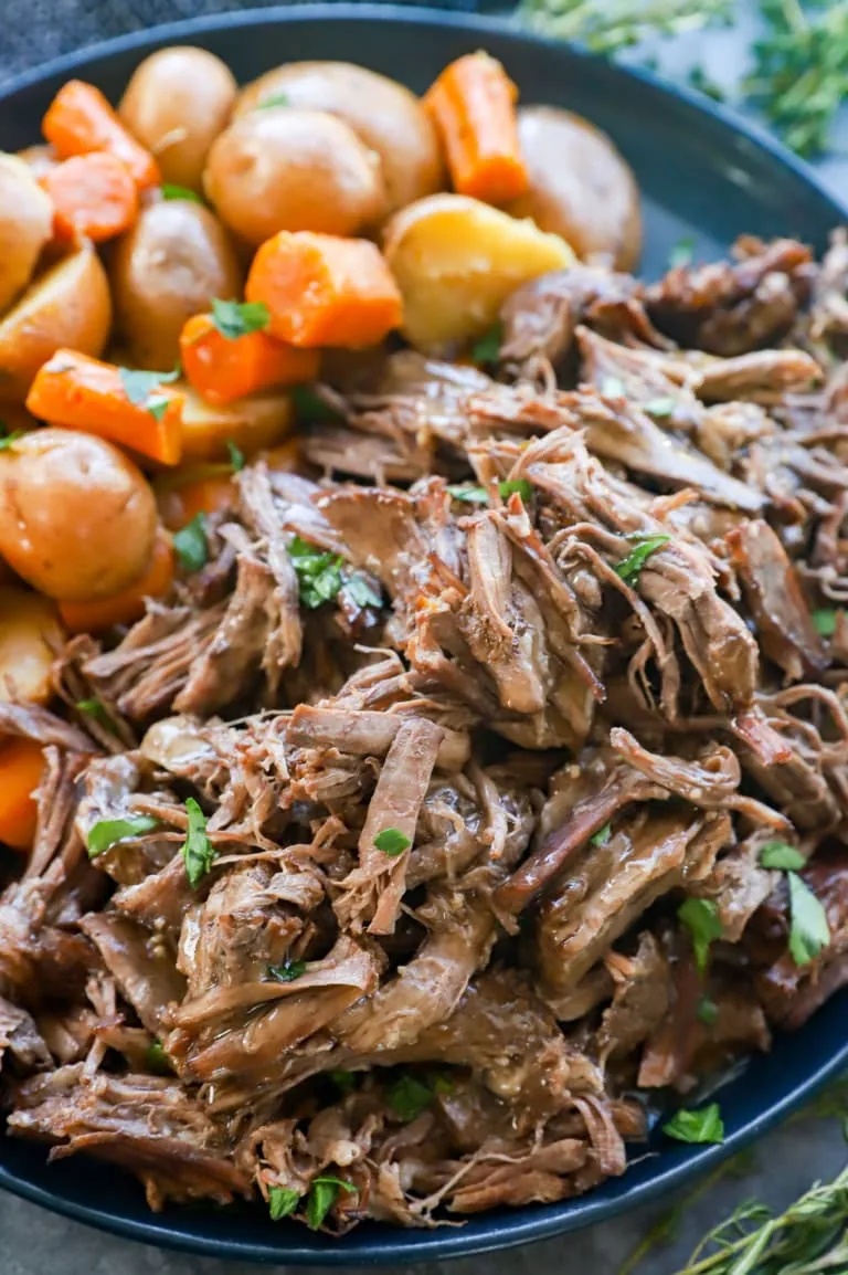 Instant pot roast beef on a plate with vegetables and gravy