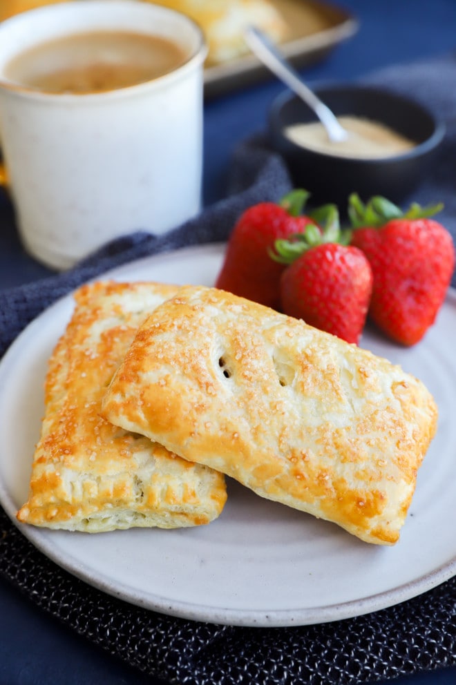 A breakfast scene with sweets on plate, fresh fruit, and coffee