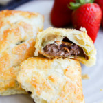 Nutella puff pastry pie cut in half with nuts on plate with strawberries