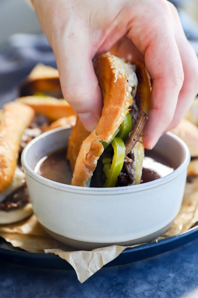 Hand sinking a meal into au jus