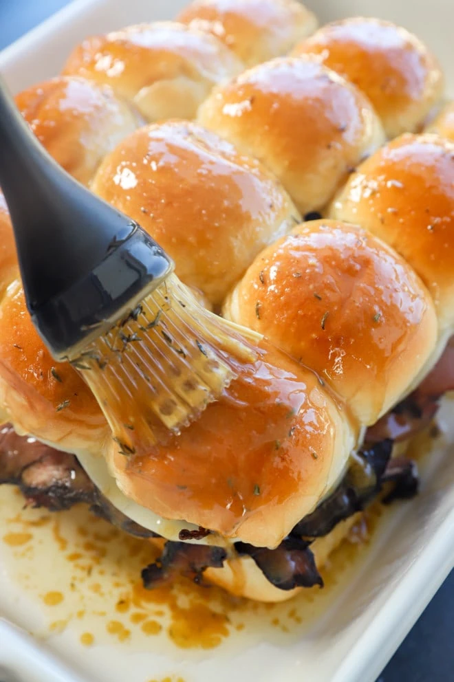 brushing butter on top of rolls