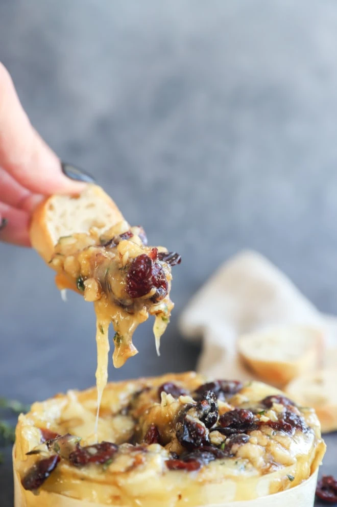 Hand lifting out toasted slice of bread with gooey cheese