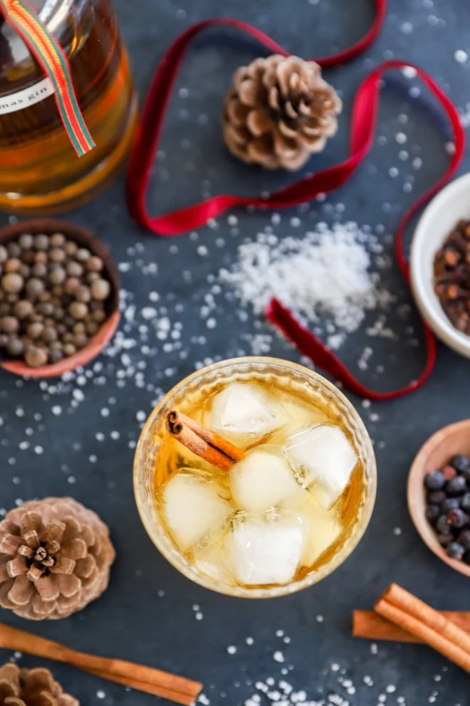 Image of a glass of christmas gin served over ice with a cinnamon stick