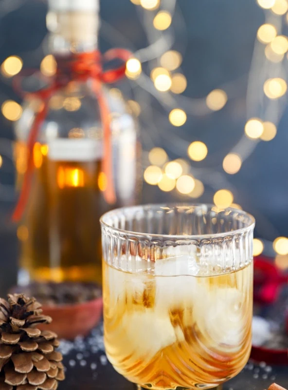 Glass of holiday cocktail over ice with lights in the background