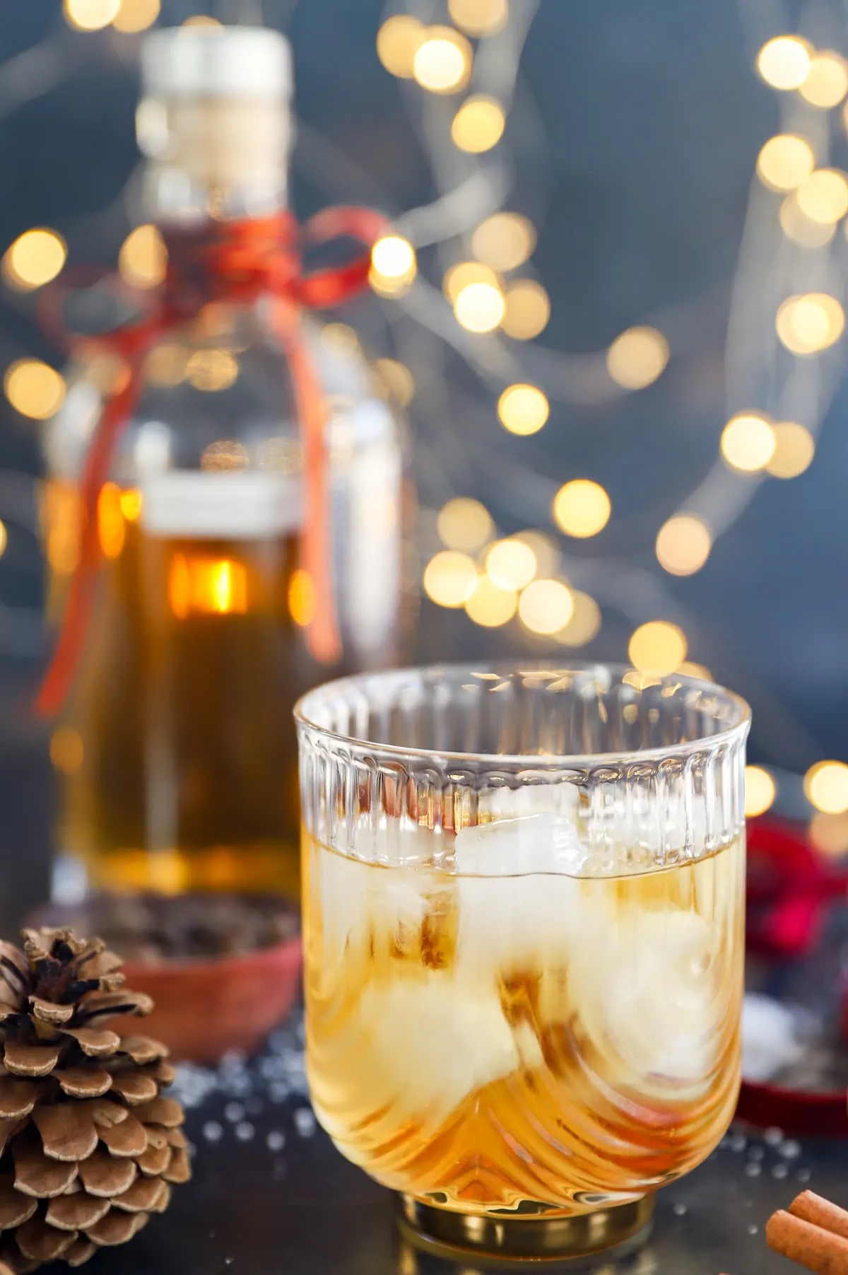 Glass of holiday cocktail over ice with lights in the background