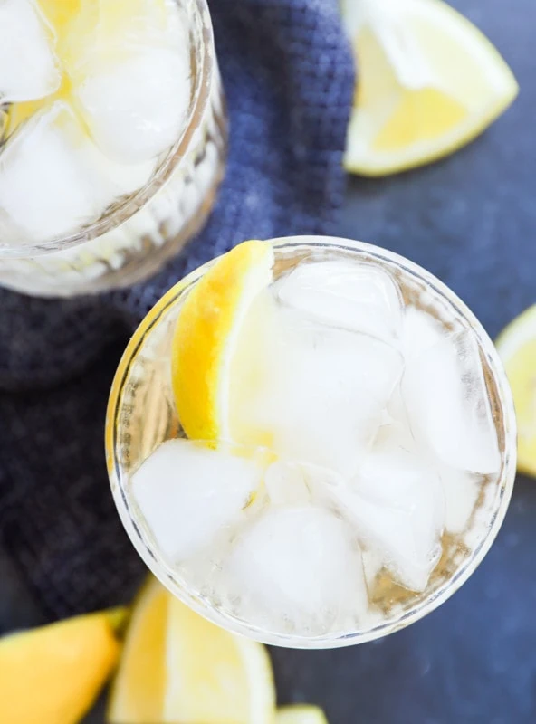 gin and ginger ale in glasses with lemon wedges and bar spoon