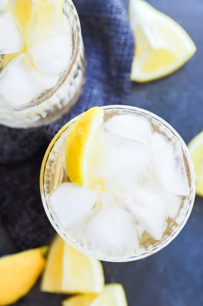 gin and ginger ale in glasses with lemon wedges and bar spoon