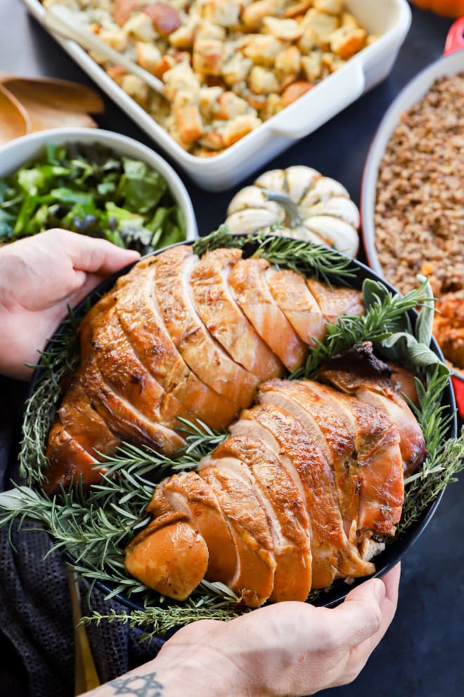 hands holding dish for thanksgiving over side dishes