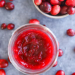 cranberry jam in a mason jar with a bowl of fresh cranberries