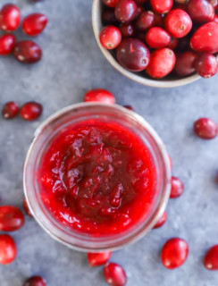 cranberry jam in a mason jar with a bowl of fresh cranberries