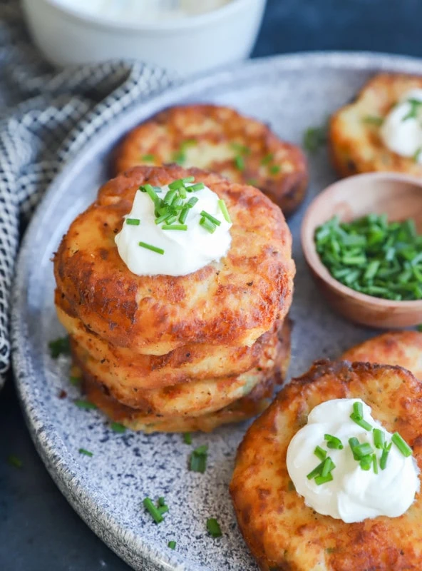 Mashed potato fritters with sour cream and chives on a serving platter