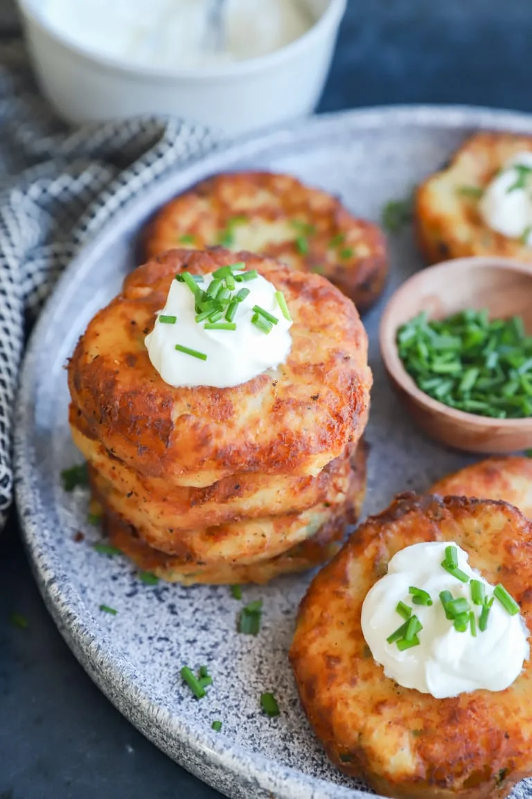 Mashed potato fritters with sour cream and chives on a serving platter