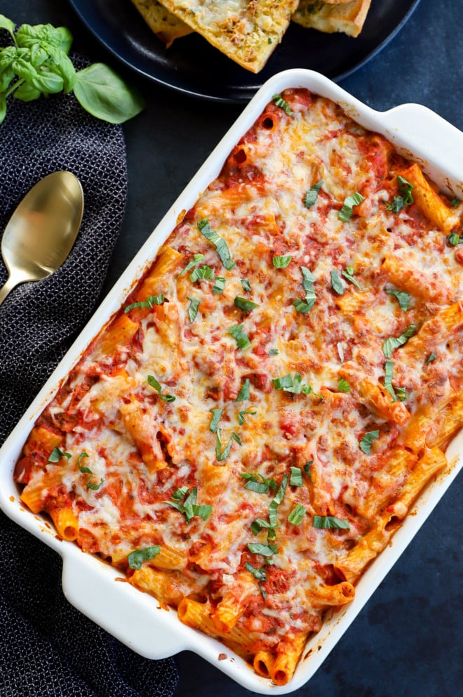 Baked pasta with cheese and fresh basil in baking pan