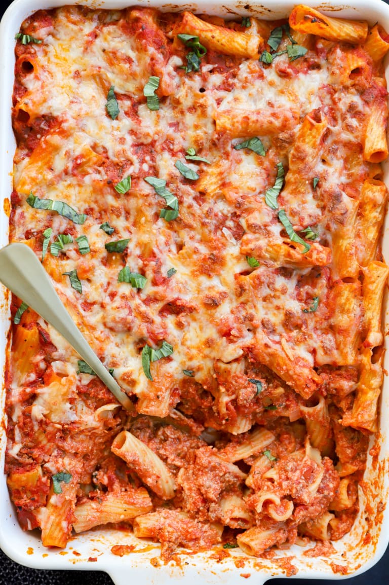 Spooning out pasta al forno from a large baking pan