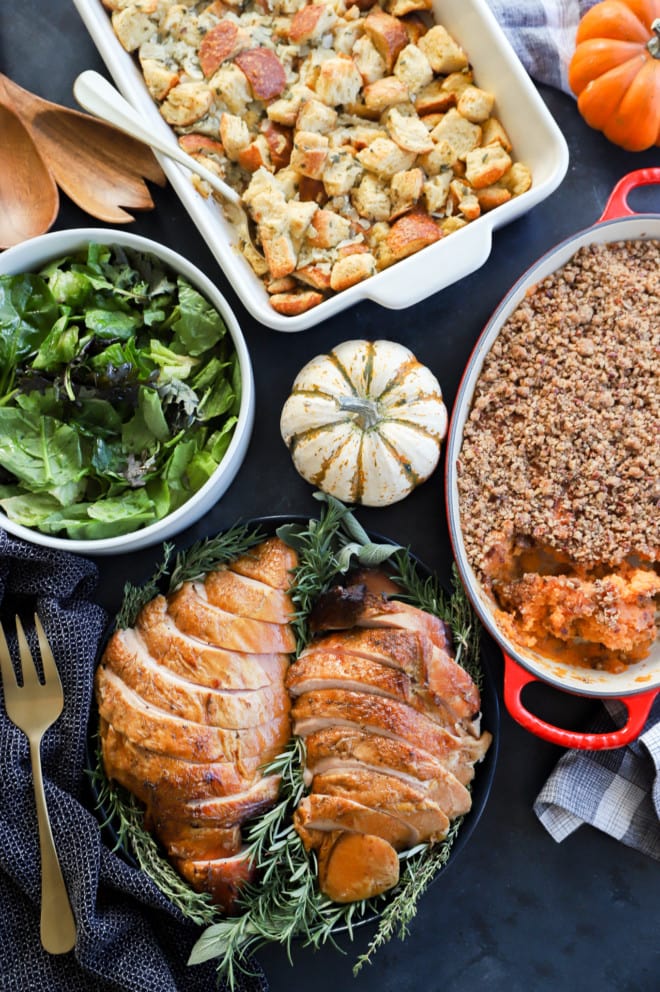 Thanksgiving table with turkey and side dishes and pumpkins