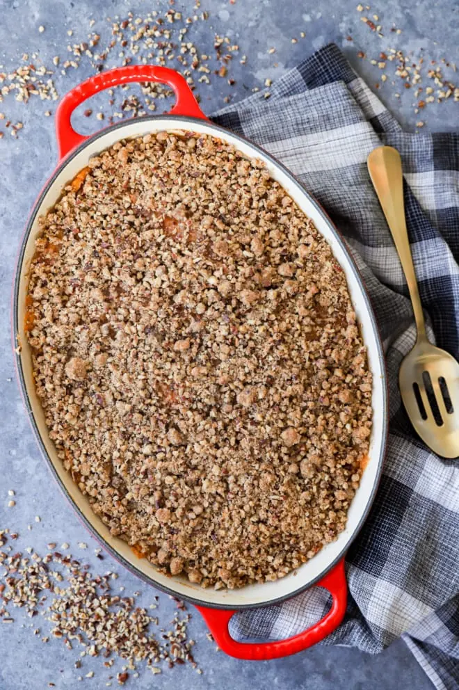 sweet potato souffle with pecan topping in baking dish with spoon