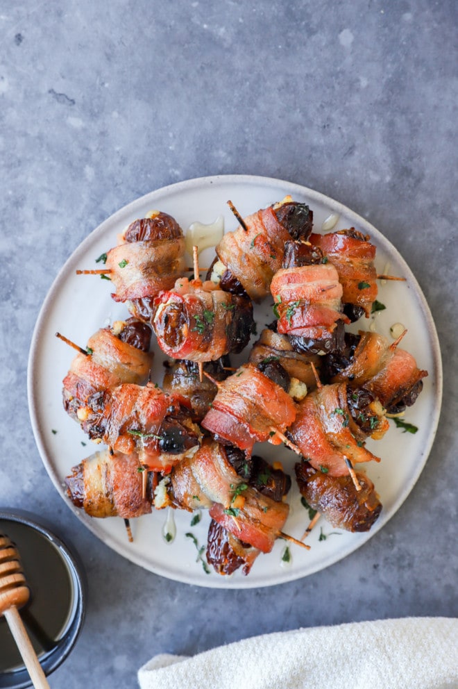 Plate of bacon wrapped dates stuffed with goat cheese and drizzled with honey