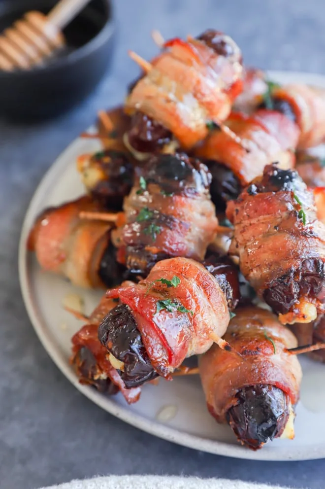 Honey with bacon wrapped dates on a plate
