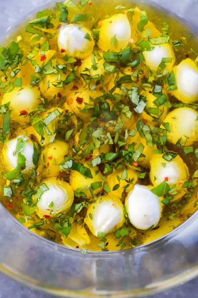 Making marinated mozzarella balls in a large bowl