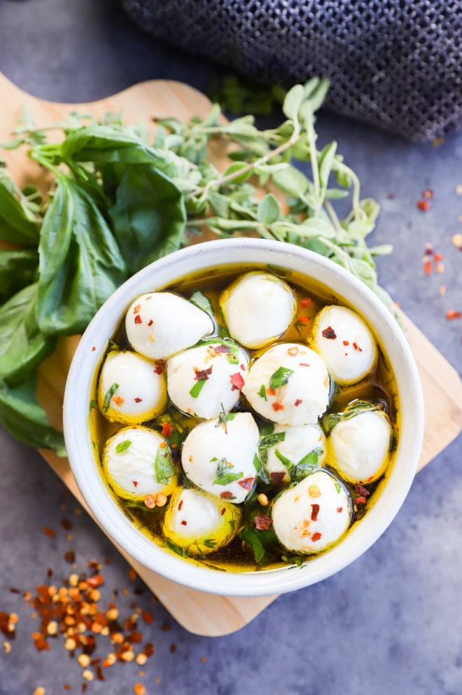 Overhead image of marinated mozzarella balls in a bowl