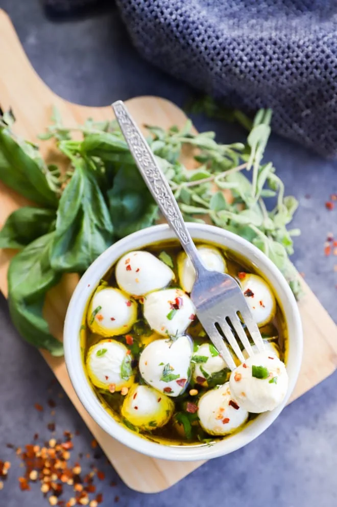 Fork with cheese ball on it with fresh herbs