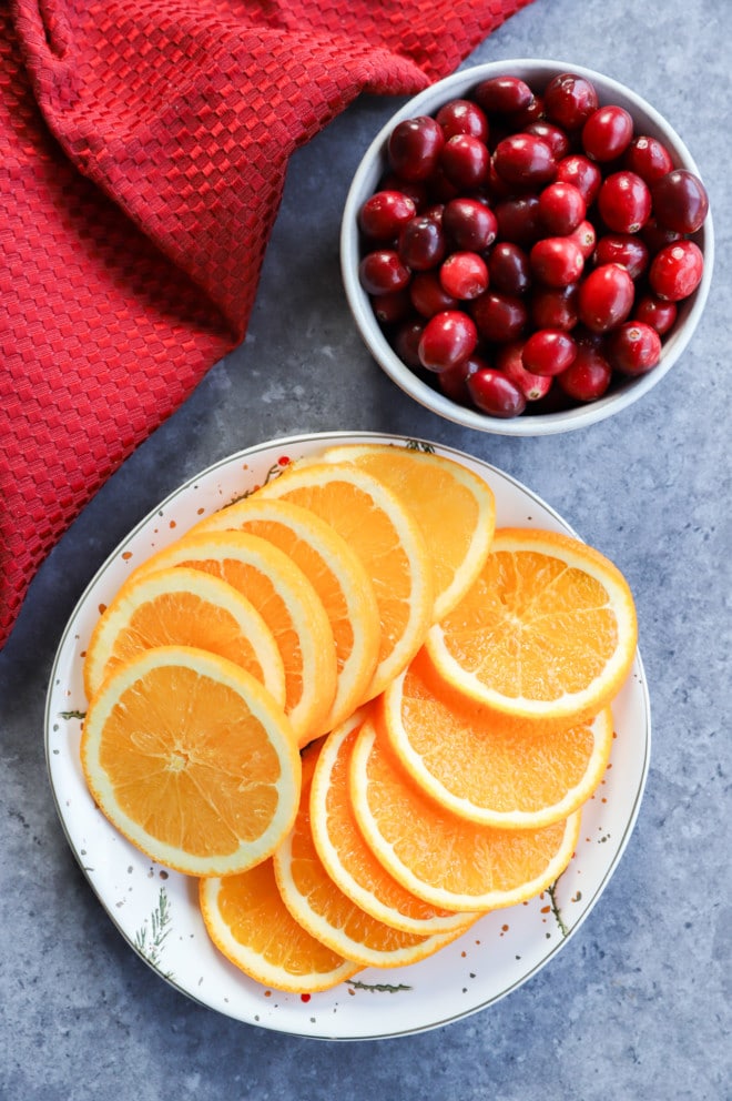orange slices on a plate and fresh cranberries in a bowl