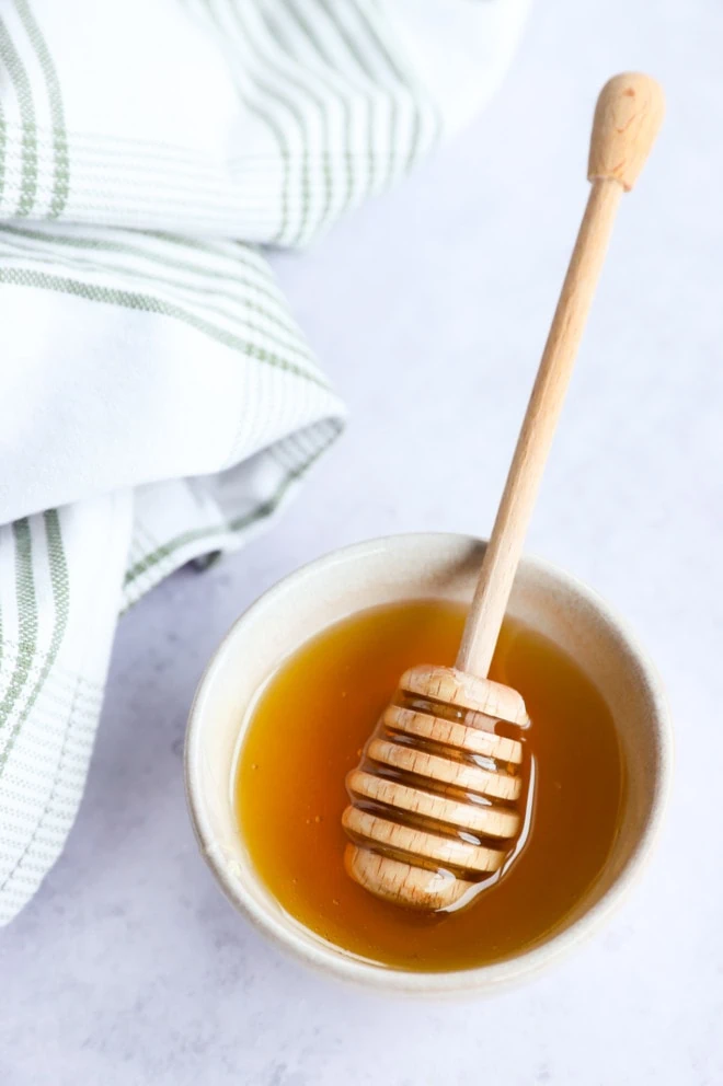 honey in a bowl with a honey stick