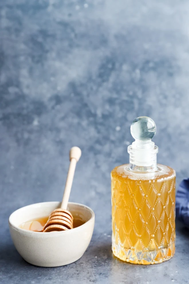 honey simple syrup in a bottle with a bowl of honey